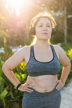 Fat woman and sports. Girl doing exercise for weight loss in the fresh air and laughing in camera after training.