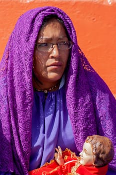 Nazarene woman covered with a purple cloak holding with her hands the figure of the child Jesus. High quality photo