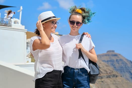Two happy smiling women, mother and teenage daughter traveling together, luxury travel on cruise ship to the famous greek island of Santorini