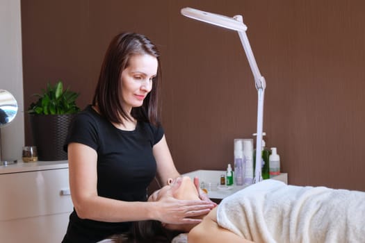 Age, beauty, face, treatment concept. Middle aged woman in cosmetologist office, receiving anti-aging massage treatment