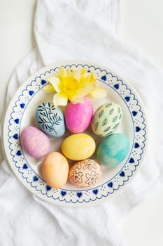 Easter eggs are painted in different colors and patterns on the plate. Top view, Easter celebration concept