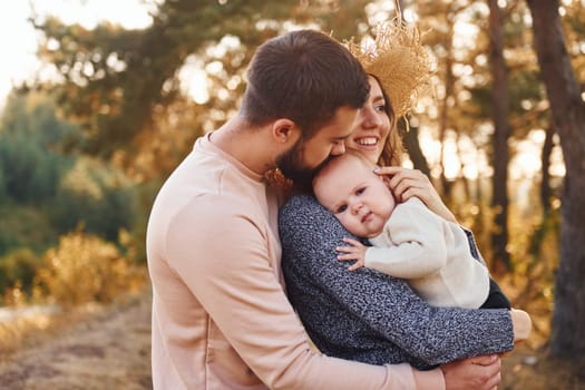 Unity of the people. Happy family of mother, family and little baby rests outdoors. Beautiful sunny autumn nature.