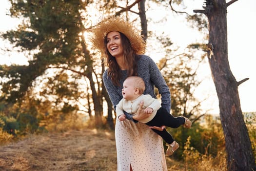 Playing together. Young mother with her little baby rests outdoors at autumn season.