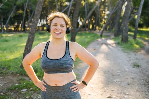 Fat woman and sports. Girl doing exercise for weight loss in the fresh air and laughing in camera after training.