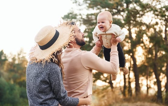 Unity of the people. Happy family of mother, family and little baby rests outdoors. Beautiful sunny autumn nature.