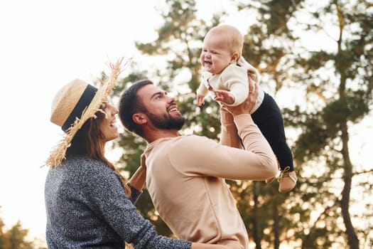 Unity of the people. Happy family of mother, family and little baby rests outdoors. Beautiful sunny autumn nature.