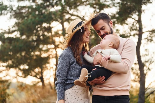 Unity of the people. Happy family of mother, family and little baby rests outdoors. Beautiful sunny autumn nature.