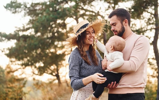 Unity of the people. Happy family of mother, family and little baby rests outdoors. Beautiful sunny autumn nature.