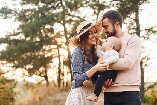 Unity of the people. Happy family of mother, family and little baby rests outdoors. Beautiful sunny autumn nature.