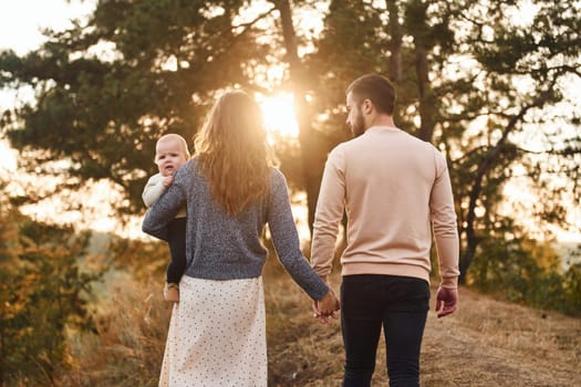 Unity of the people. Happy family of mother, family and little baby rests outdoors. Beautiful sunny autumn nature.