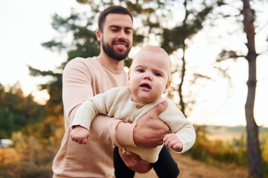 Bearded father playing with his child outdoors at sunny daytime outdoors.