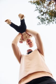 Bearded father playing with his child outdoors at sunny daytime outdoors.