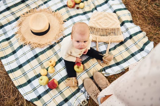 Top view. Having picnic. Young mother with her little baby rests outdoors at autumn season.