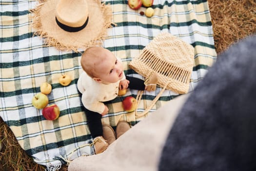 Top view. Having picnic. Young mother with her little baby rests outdoors at autumn season.