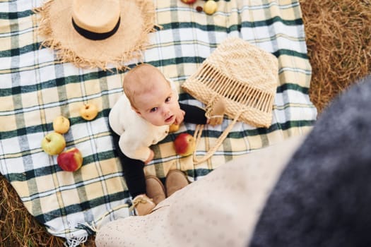 Top view. Having picnic. Young mother with her little baby rests outdoors at autumn season.