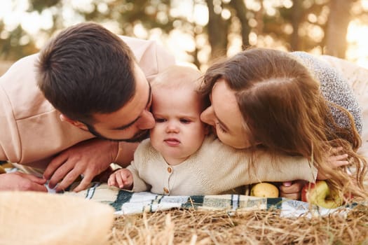 Haves picnic. Happy family of mother, family and little baby rests outdoors. Beautiful sunny autumn nature.