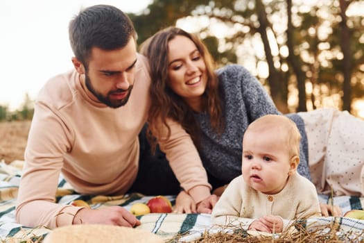 Haves picnic. Happy family of mother, family and little baby rests outdoors. Beautiful sunny autumn nature.