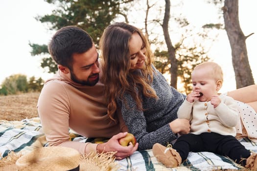 Haves picnic. Happy family of mother, family and little baby rests outdoors. Beautiful sunny autumn nature.