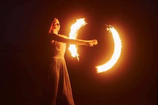 Photo with a long exposure. Fire show by woman in dress in night Carphatian mountains. Beautiful landscape.