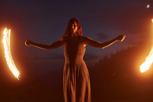 Photo with a long exposure. Fire show by woman in dress in night Carphatian mountains. Beautiful landscape.