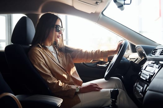 Side view of fashionable beautiful young woman that is inside her modern automobile.