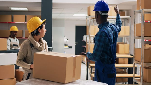 Male worker giving package of goods to supervisor, helping to scan barcodes on boxes and plan stock logistics for merchandise. Two people scanning products with scanner and tablet.