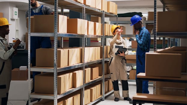 African american man using scanner and tablet, scanning barcodes of goods packed in cardboard boxes. Male employee working in storage room with cargo and merchandise for shipment.