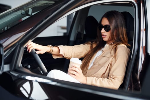 Coffee break. Fashionable beautiful young woman and her modern automobile.