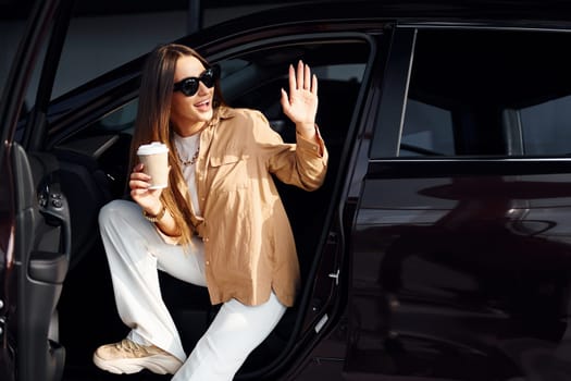 Coffee break. Fashionable beautiful young woman and her modern automobile.