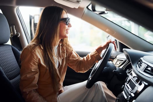 Side view of fashionable beautiful young woman that is inside her modern automobile.