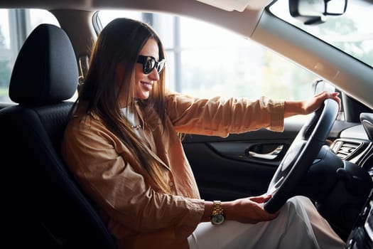 Side view of fashionable beautiful young woman that is inside her modern automobile.