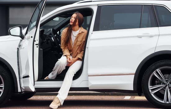 Looks outside from the car. Fashionable beautiful young woman and her modern automobile.