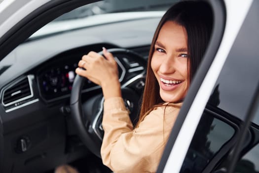 Driving car. Fashionable beautiful young woman and her modern automobile.