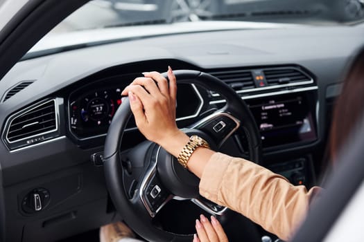 Driving car. Fashionable beautiful young woman and her modern automobile.