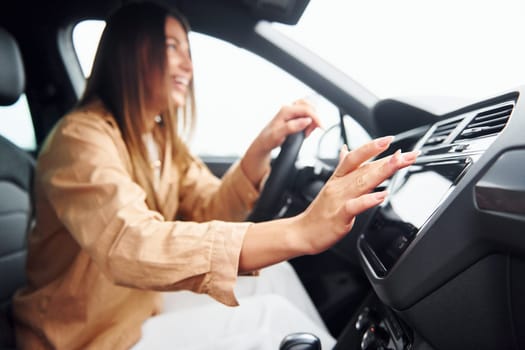 Side view of fashionable beautiful young woman that is inside her modern automobile.