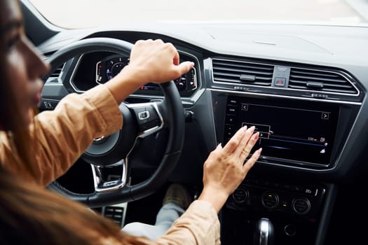 Driving car. Fashionable beautiful young woman and her modern automobile.