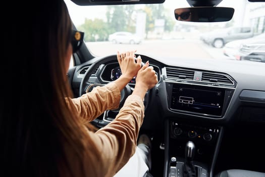 Driving car. Fashionable beautiful young woman and her modern automobile.