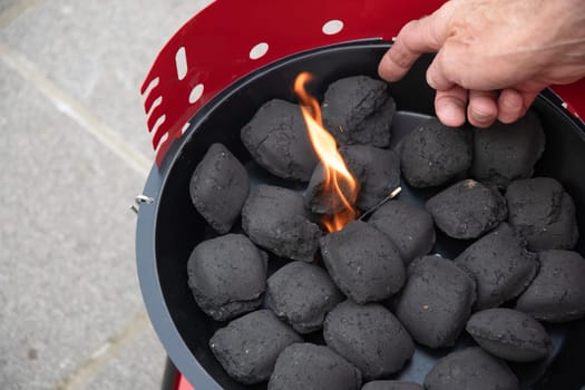 a man lights a fire with a lighter special charcoals for a barbecue a barbecue house on the terrace prepares a place for a barbecue. High quality photo