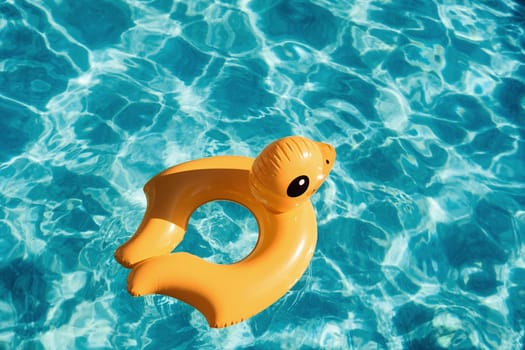 Top view of yellow duck toy for swimming in the pool at daytime.