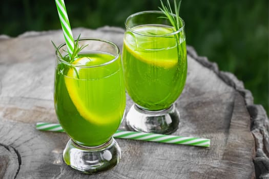 Homemade summer refreshing tarragon lemon drink on patio table.