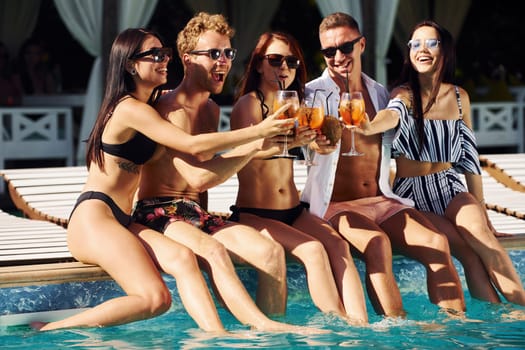 Group of young happy people have fun in swimming pool at daytime.