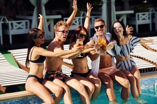 Group of young happy people have fun in swimming pool at daytime.