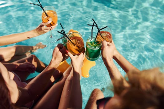 Top view of group of young happy people that have fun in swimming pool at daytime.