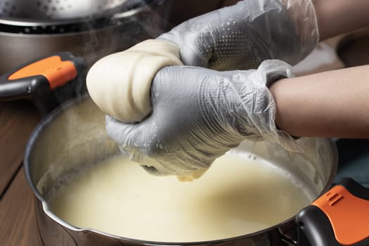 Making mozzarella cheese. Pulling out the cheese clot after heating in whey.