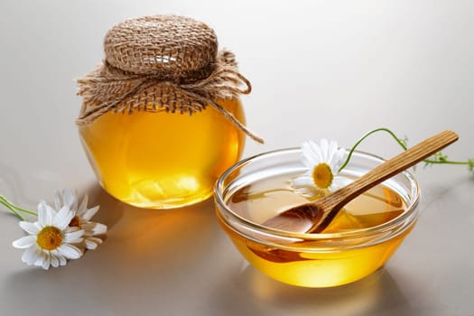 Chamomile syrup in a small bowl and jar on the kitchen table.