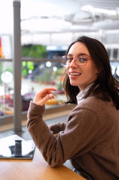 Modern technologies and communication. Portrait of happy woman with tablet computer sitting at her desk. Young female person studying or working online on touch pad. Vertical photo