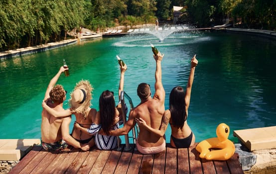 Taking a rest together. Group of young happy people have fun in swimming pool at daytime.