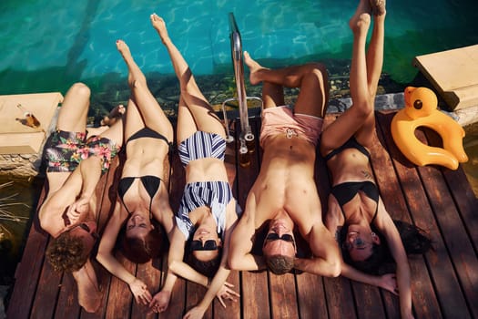 Taking a rest together. Group of young happy people have fun in swimming pool at daytime.