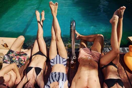 Taking a rest together. Group of young happy people have fun in swimming pool at daytime.