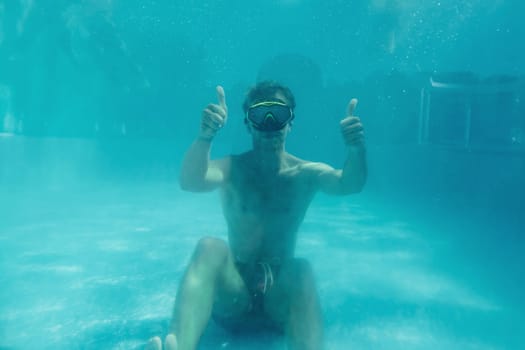 Man swimming underwater in the pool at daytime. Having fun.